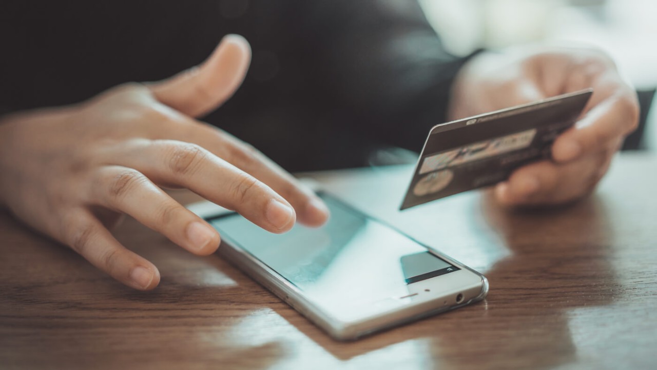 A person enters his credit card number into his cell phone