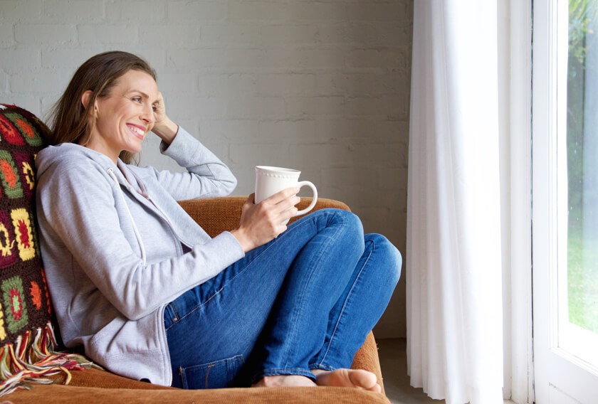 A 30-something woman relaxes and looks out the window.