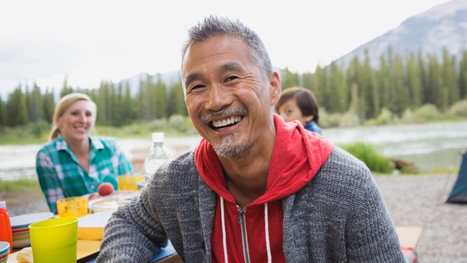 Un homme sourit en campant avec sa famille.