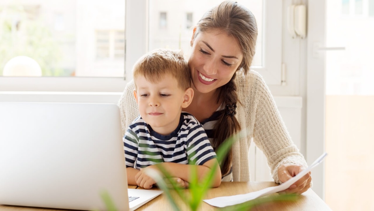 Une maman et son jeune fils regardent les informations d'investissement sur un ordinateur portable.
