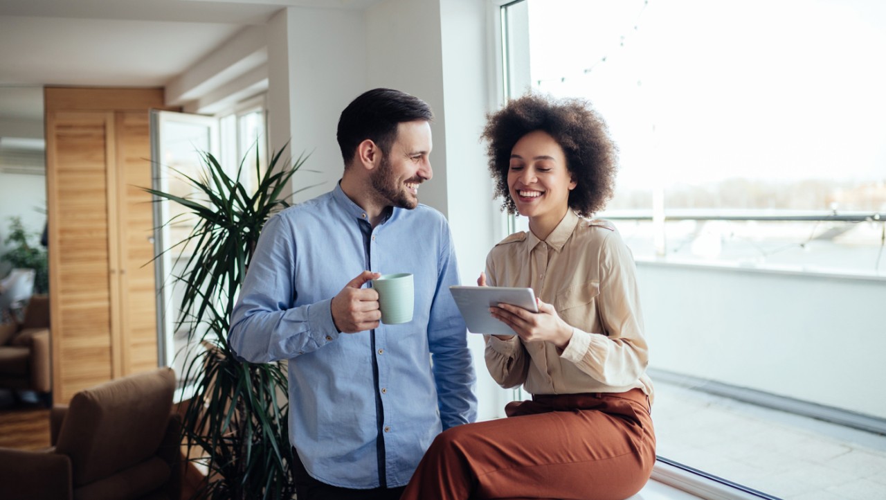 Un jeune couple sourit en regardant des documents pour son REER de conjoint.